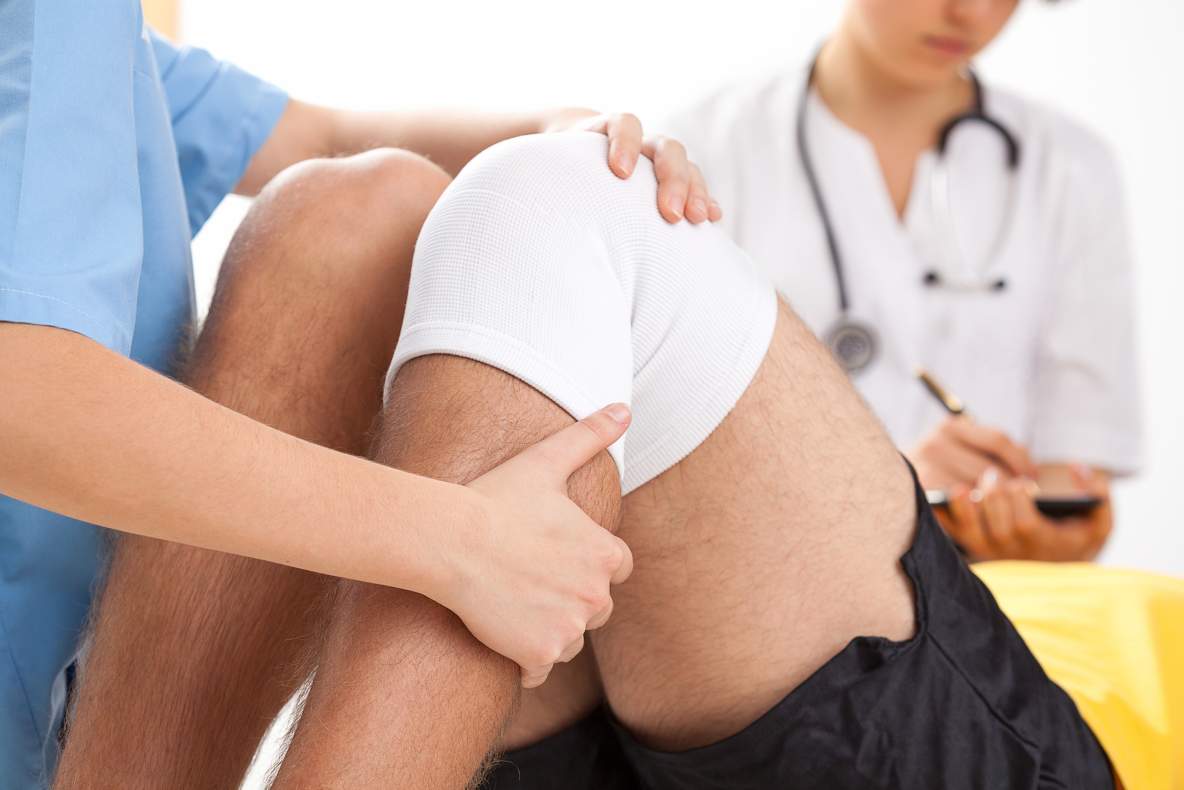 Een arts onderzoekt een patiënt na een knie-operatie