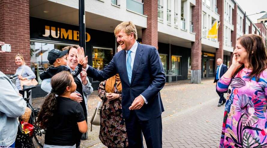 Koning geeft high five in de wijk