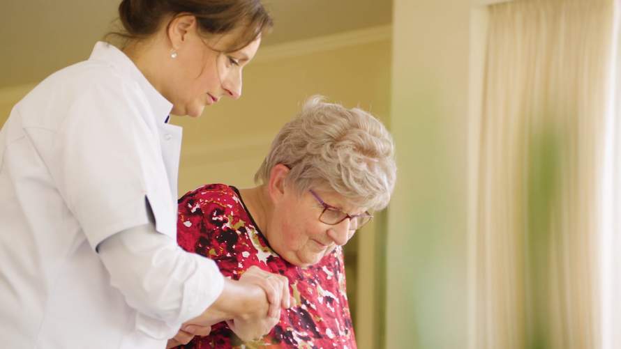 Wijkverpleegkundige helpt oudere vrouw