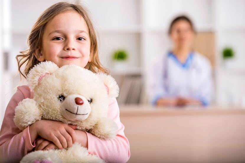 Meisje houdt teddybeer vast met poh-jeugd op achtergrond