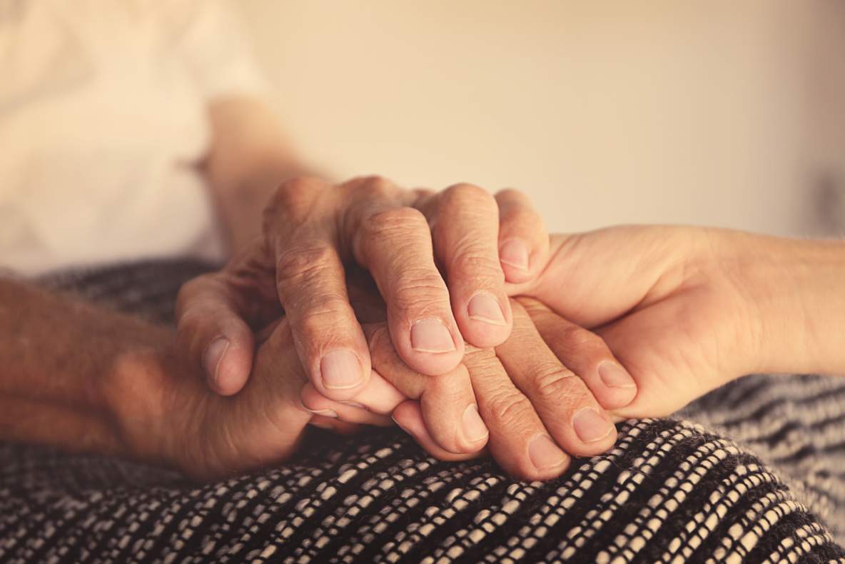 Oudere en jongere handen houden elkaar vast