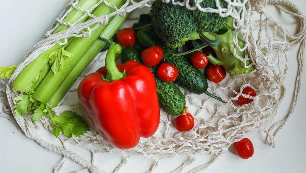 Boodschappentasje met bleekselderij, paprika, broccolu en tomaten