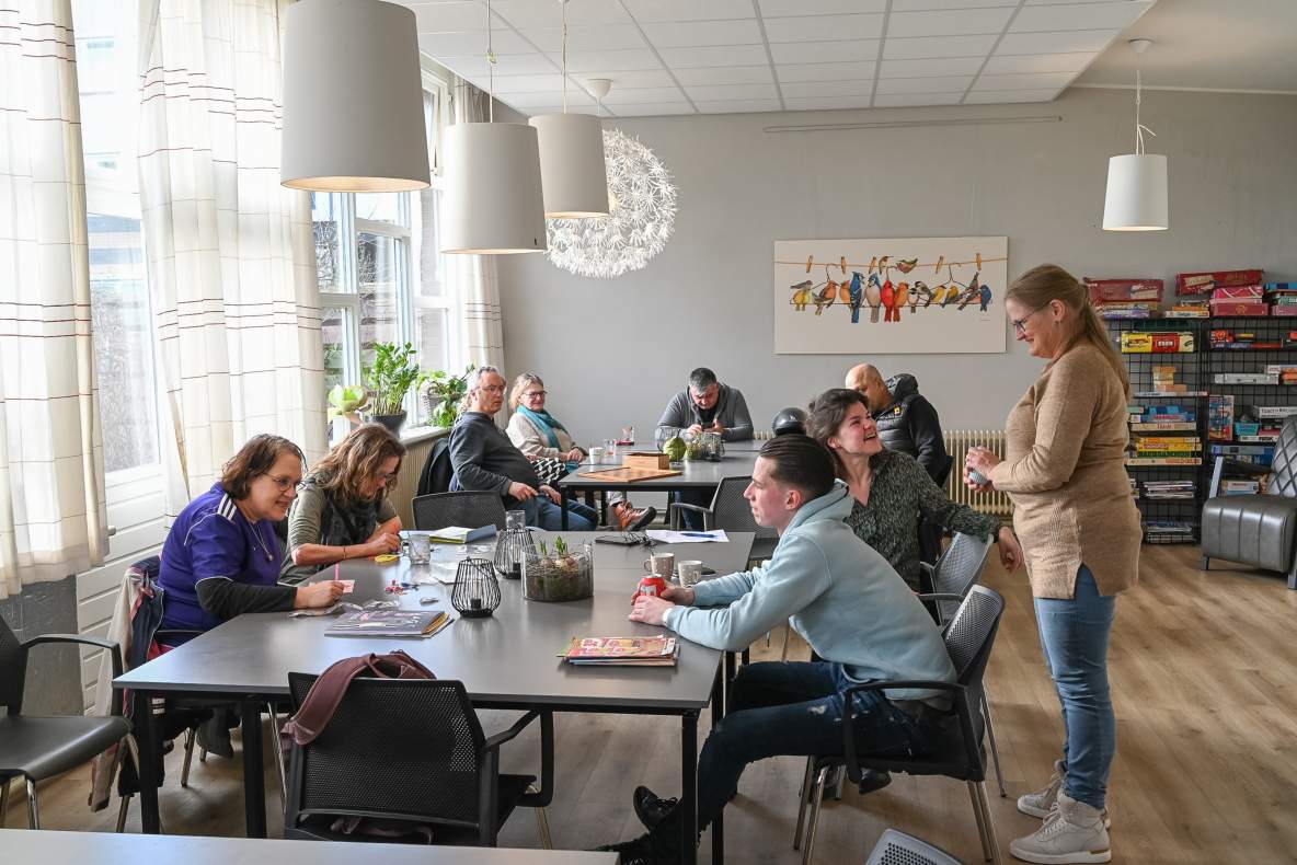 Verschillende personen zijn met elkaar in gesprek of ondernemen een activiteit aan tafel