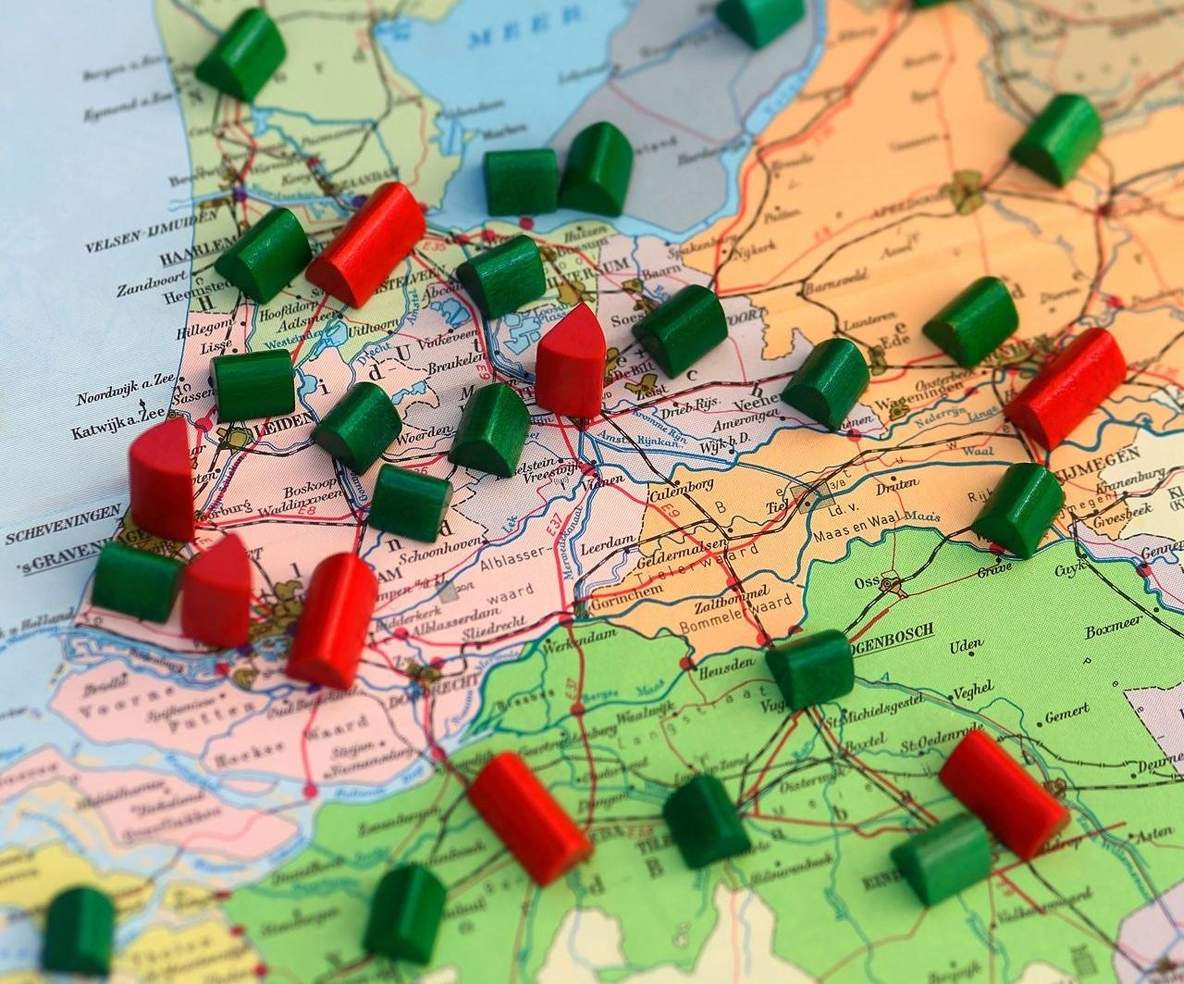 Landkaart van Nederland met meerdere rode en groene monopoly-huisjes op de kaart