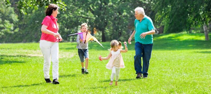 Opa en oma rennen met vliegers samen de kleinkinderen