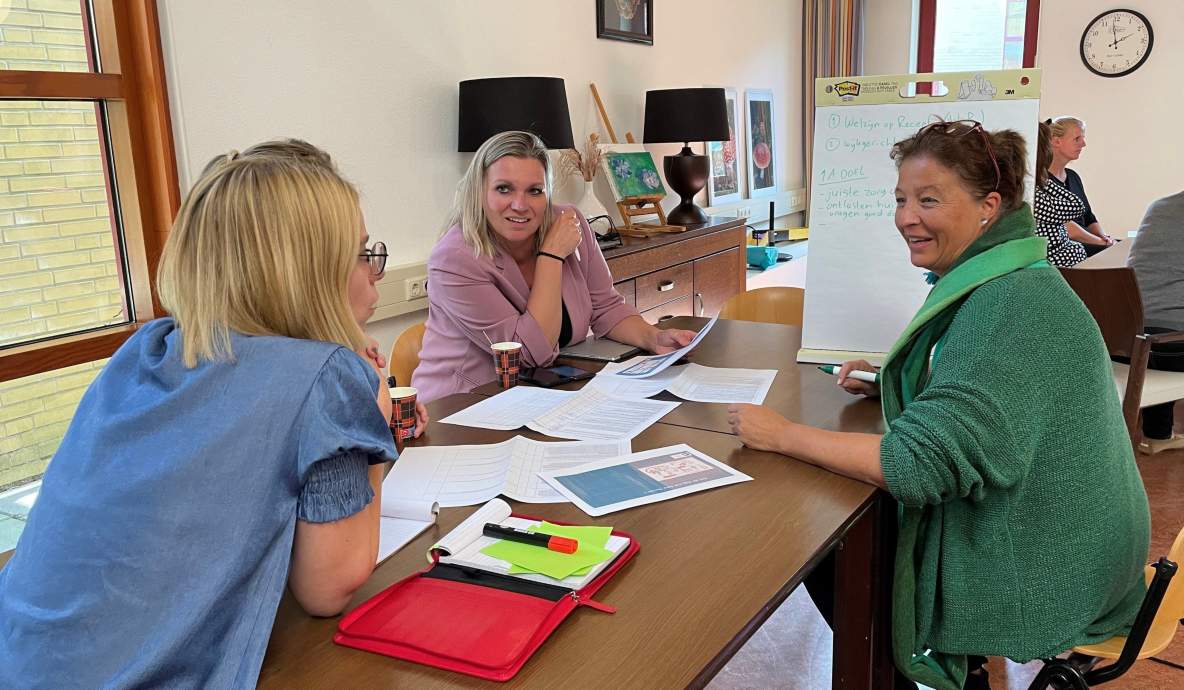 Drie vrouwen overleggen aan tafel en schrijven de bevindingen op