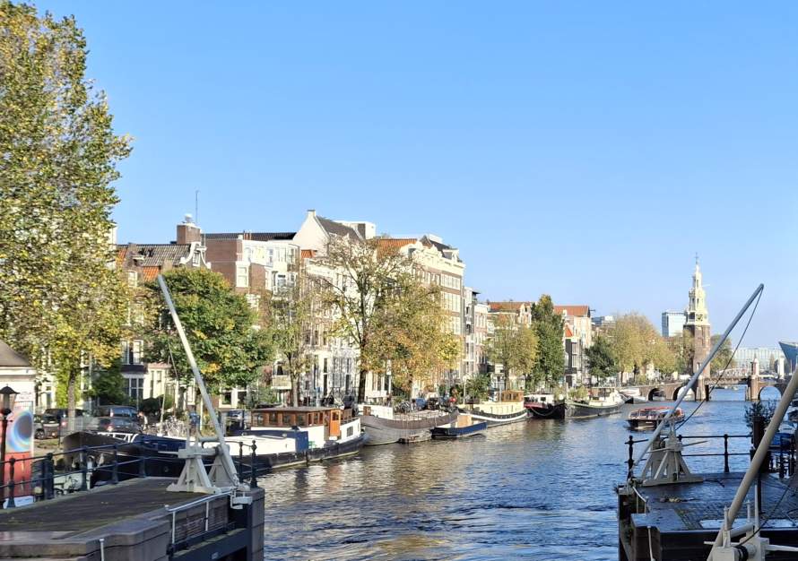 Uitzicht op Amsterdamse gracht met grachtenpanden, boten en in de verte een toren