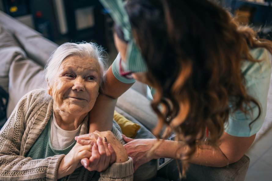 Oude mevrouw kijkt omhoog naar verzorgende